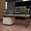 custom glass jewelry display counter with gold frame and storage cabinet
