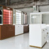 Custom illuminated optical wall showcase cabinet with brand logo display and lower storage drawers