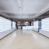 Custom optical store furniture arranged in a factory with illuminated wall shelves and white storage cabinets