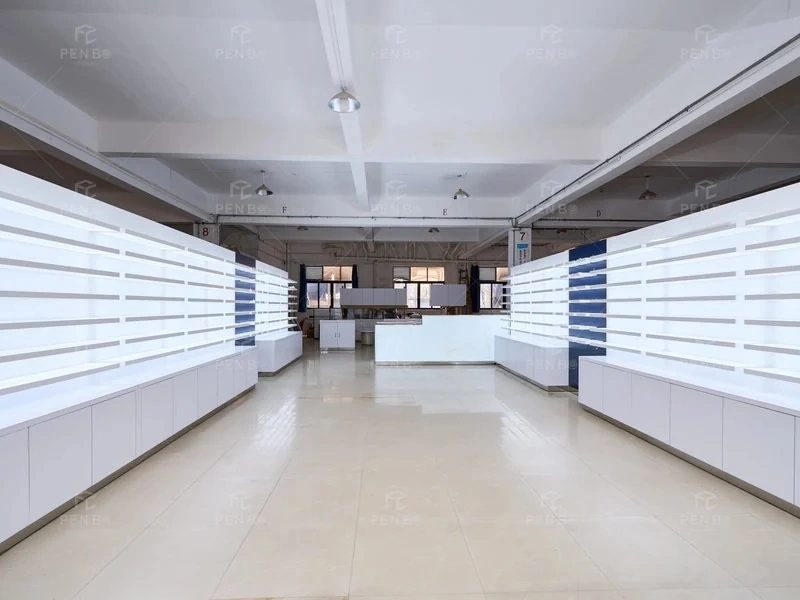 Custom optical store furniture arranged in a factory with illuminated wall shelves and white storage cabinets